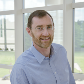 Photo of a smiling man in front of windows